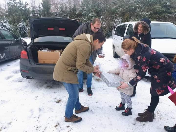 Przekazywanie zapakowanych prezentów przy samochodach zimą.