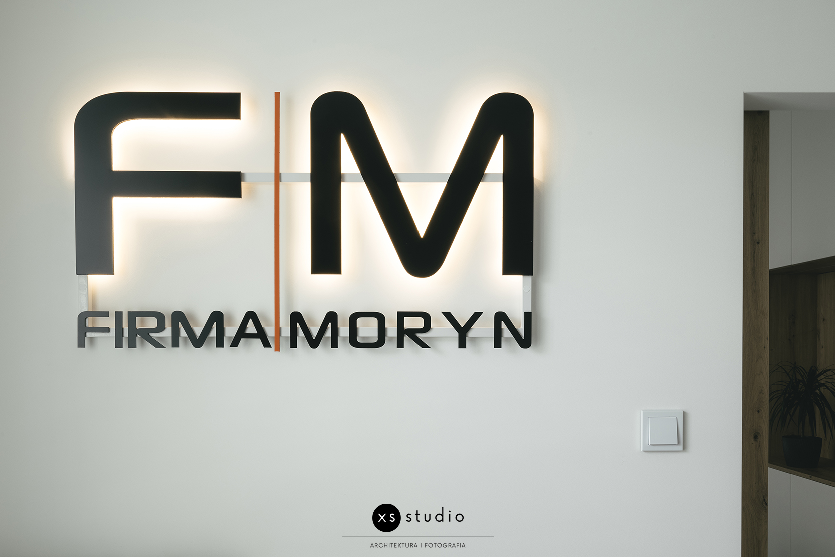 Podświetlane logo Firmy Moryn na ścianie biura.