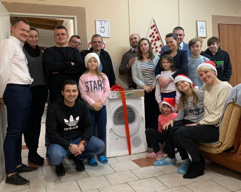 Uczestnicy spotkania z prezentami i sprzętem gospodarstwa domowego.